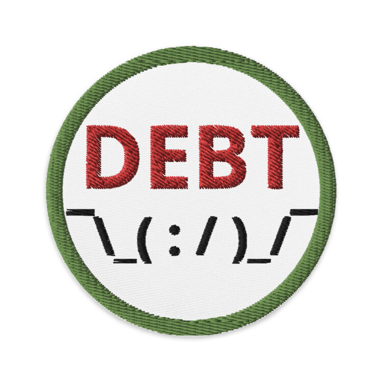 3 inch circle patch with a green outline around a white background. Inside the circle is the word "DEBT" written in red. Using ASCII art, below the word "debt" is the picture of human being shrugging their shoulders. denimandpatches