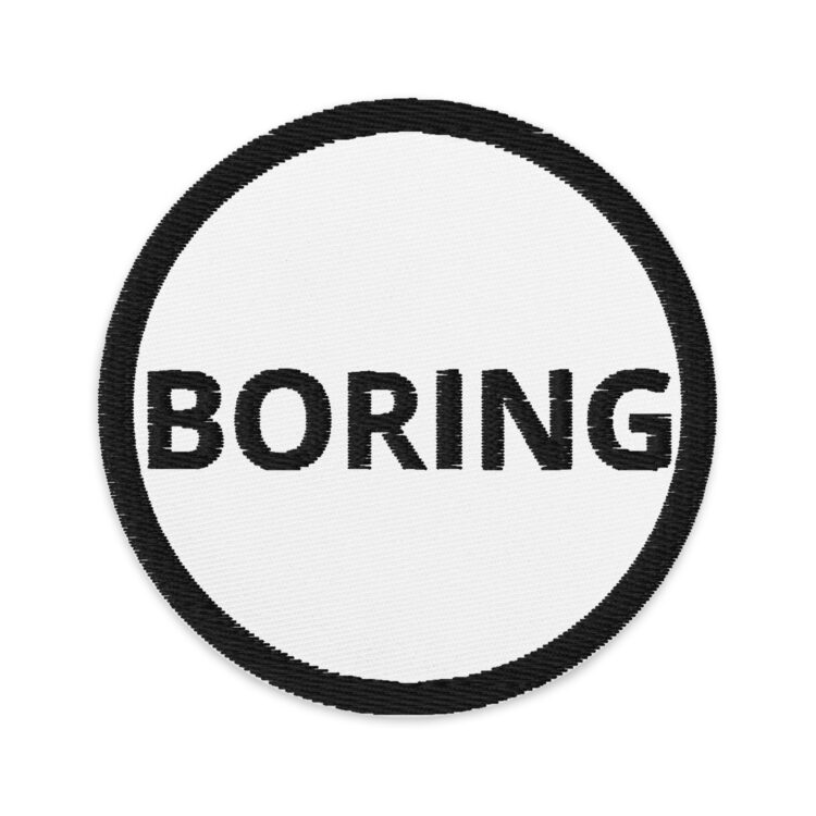 3 inch circle patch with a black outline around a white background. With the word "BORING" centered in the middle written in a black lettering. denimandpatches