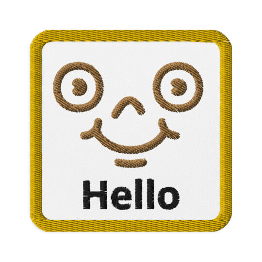3 inch square shaped patch with a gold outline around a white background. With a brown detailed smiley face centered in the square. Right underneath the face is the word "Hello". denim and patches