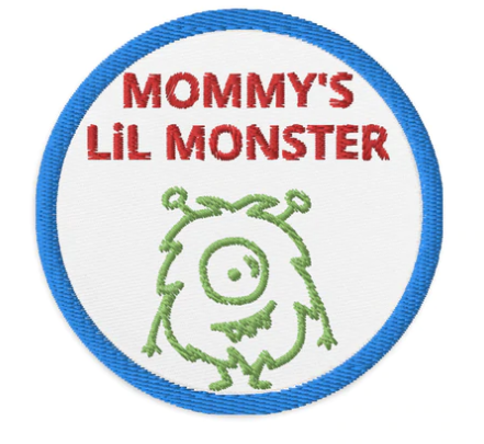3 inch circle patch with a blue outline around a white background. With the words "MOMMY'S Lil MONSTER" written in red centered at the top of the patch. Above the outline of a green furry circle monster with antennas sticking out of its head. denimandpatches